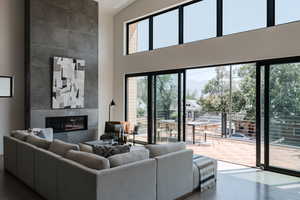 Living room with wood finished floors, a tiled fireplace, a high ceiling, and a mountain view