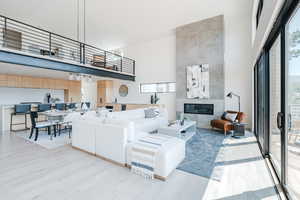 Living room featuring a towering ceiling, a tiled fireplace, and light wood-type flooring