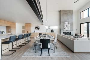 Dining room featuring a fireplace, light wood finished floors, and a high ceiling