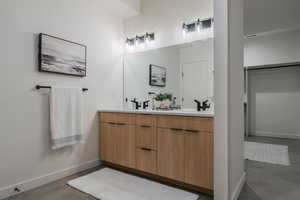 Bathroom with double vanity and concrete flooring