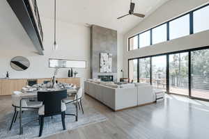 Living area featuring light wood-style floors, high vaulted ceiling, a tile fireplace, and ceiling fan