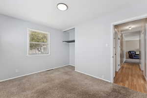 Unfurnished bedroom featuring light carpet and a closet
