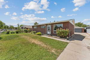 Single story home with an outbuilding, brick siding, a front yard, and a detached garage