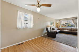 Living area with plenty of natural light, wood finished floors, and a ceiling fan