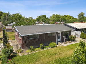Front aerial view of property with a gate, brick siding, roof with shingles