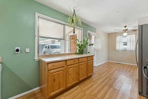 Kitchen featuring ceiling fan, light wood-look vinyl floors, light countertops, and stainless steel appliances