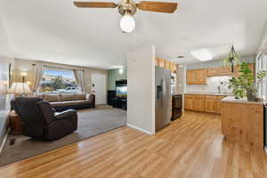 Kitchen with open floor plan, light countertops, stainless steel refrigerator with ice dispenser, and light wood-style vinyl floors