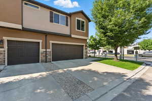 Traditional home with stucco siding, a garage, concrete driveway, and stone siding
