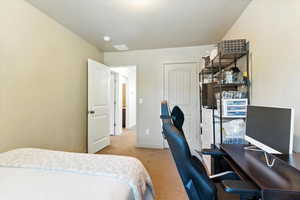 Bedroom with light carpet and an office area
