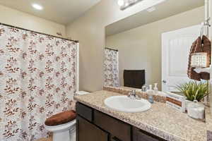 Bathroom with vanity, curtained shower, and recessed lighting