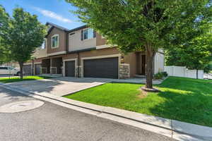 View of front facade featuring stucco siding, stone siding, an attached garage, and concrete driveway