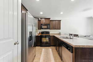 Kitchen with black appliances, recessed lighting, dark brown cabinets, light countertops, and a peninsula