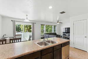 Kitchen featuring healthy amount of natural light, dark brown cabinets, stainless steel dishwasher, ceiling fan, and recessed lighting