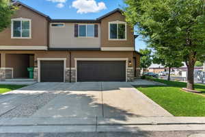 Traditional-style house with stucco siding, driveway, an attached garage, and stone siding