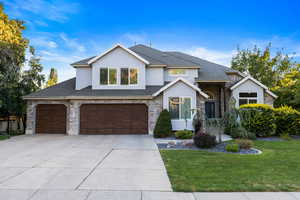 View of front of home featuring stone siding, stucco siding, driveway, an attached garage, and a shingled roof