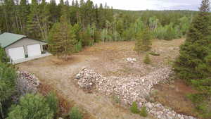 View of yard with a detached garage, an outdoor structure, and a forest view