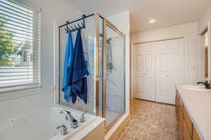 Bathroom featuring a newly tiled shower stall, vanity, a garden tub, healthy amount of natural light, and recessed lighting
