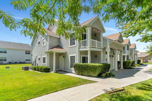 View of front of house with a shingled roof, a front lawn, and a balcony