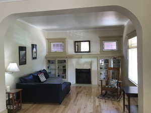 Living area with arched walkways, wood finished floors, built-in leaded glass , and original fireplace with new gas insert