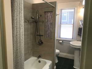 Bathroom with tile patterned flooring and shower / bathtub combination with stain glass accents. Original 6 panel door on barn slider.