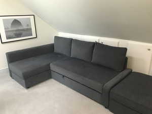 Carpeted living area with lofted ceiling. Storage behind couch.