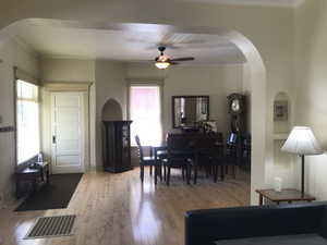 Dining area featuring arched walkways, crown molding, solid maple flooring, and ceiling fan