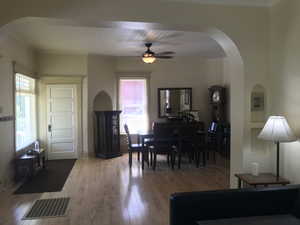 Dining room with solid maple flooring, crown molding, ceiling fan, and arched walkways. Note the architecural cubbys and recessed built-ins.