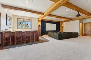Carpeted cinema room featuring beam ceiling, recessed lighting, and bar