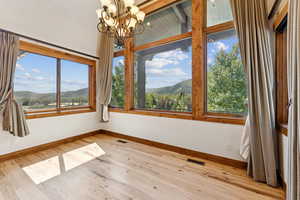Unfurnished dining area featuring a mountain view, light wood-type flooring, a chandelier, and healthy amount of natural light