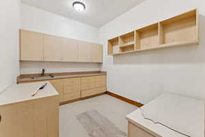 Kitchen with light brown cabinets, concrete flooring, and open shelves
