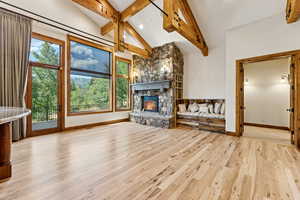 Unfurnished living room featuring beam ceiling, wood finished floors, a fireplace, recessed lighting, and high vaulted ceiling