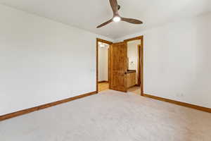 Unfurnished bedroom with light colored carpet, connected bathroom, and ceiling fan