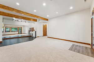 Unfurnished living room with beamed ceiling, recessed lighting, carpet floors, and track lighting