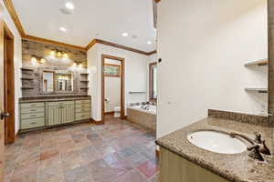 Full bathroom with two vanities, recessed lighting, crown molding, a bath, and stone tile flooring