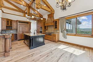 Kitchen featuring tasteful backsplash, brown cabinets, high vaulted ceiling, an island with sink, and recessed lighting