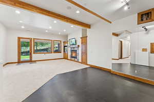 Unfurnished living room featuring recessed lighting, a tiled fireplace, and beam ceiling