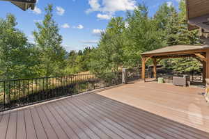 Wooden terrace featuring a gazebo and view of wooded area