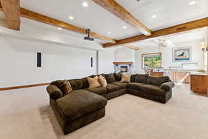 Living room featuring beam ceiling, a fireplace, recessed lighting, and light colored carpet