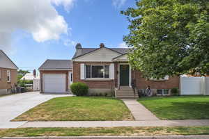 View of front of house featuring an attached garage, concrete driveway, brick siding, a shingled roof, and a chimney