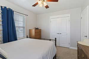 Bedroom featuring light carpet, a closet, and a ceiling fan