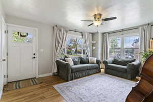 Living area featuring light wood-style flooring, a textured ceiling, and ceiling fan