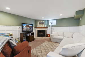 Carpeted living area with a brick fireplace, a wainscoted wall, recessed lighting, and a decorative wall