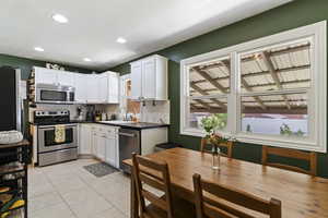 Kitchen with appliances with stainless steel finishes, decorative backsplash, light tile patterned flooring, white cabinets, and recessed lighting