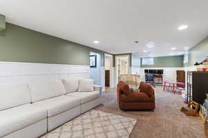 Living area with recessed lighting, carpet flooring, and a wainscoted wall