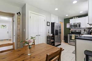 Kitchen with appliances with stainless steel finishes, decorative backsplash, light tile patterned flooring, white cabinets, and recessed lighting