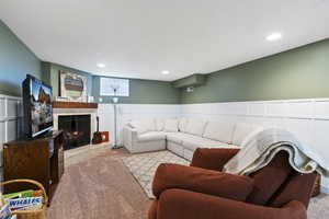Living area with a wainscoted wall, carpet, a decorative wall, a brick fireplace, and recessed lighting