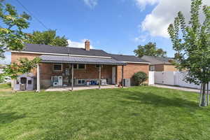 Rear view of house with a gate, a patio area, brick siding, and a chimney