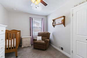 Bedroom featuring carpet floors, a textured ceiling, a crib, and ceiling fan