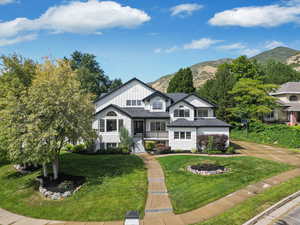 View of front of home with board and batten siding, concrete driveway, a front lawn, and a garage