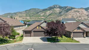 View of front of property with brick siding, driveway, a garage, a mountain view, and a front yard